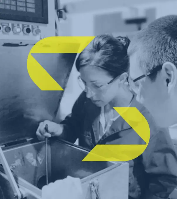 woman and man employees inspecting machine