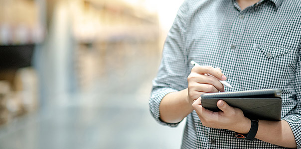 man on ipad taking stock in warehouse